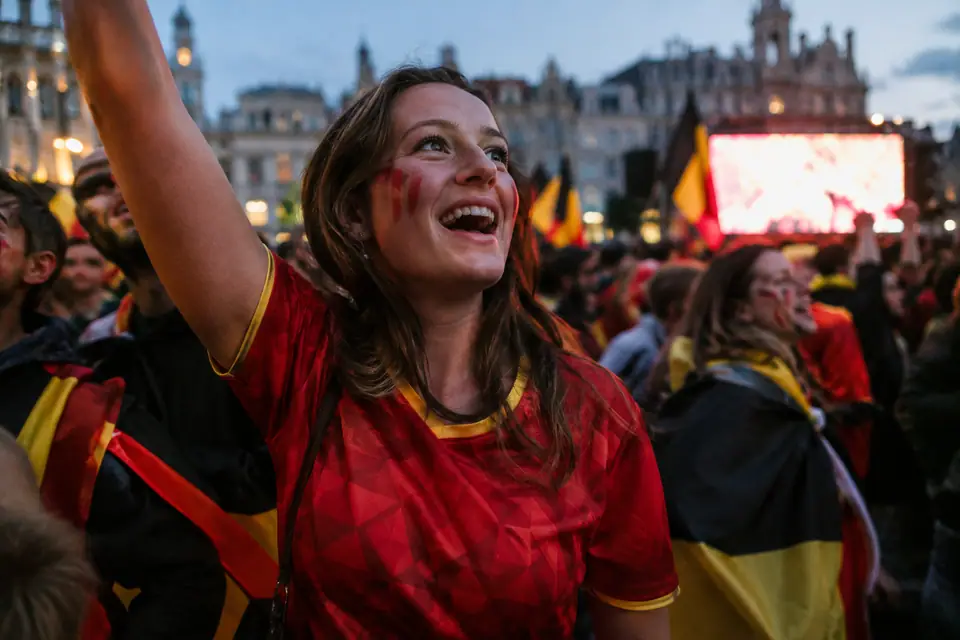 Jeune supportrice en maillot rouge à losanges qui encourage son équipe sur une place bondée