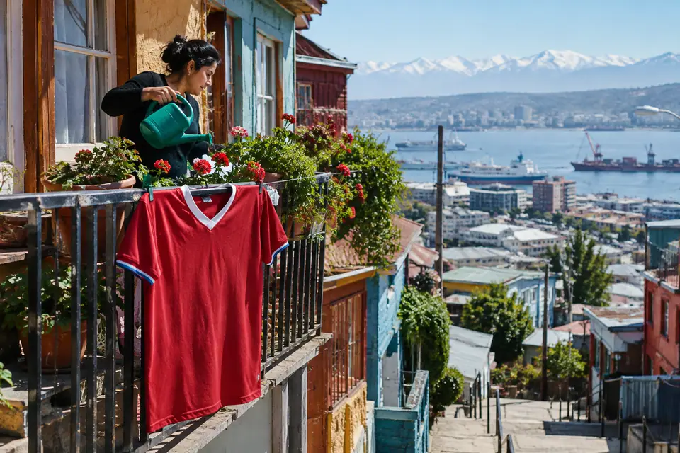 Maillot de foot rouge rétro accroché au balcon d'une maison colorée au-dessus d'une ville portuaire