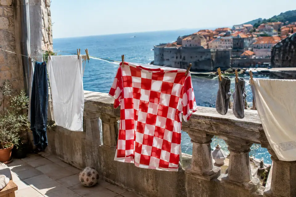 Maillot de foot à damier rouge et blanc qui sèche sur un balcon en pierre face à la mer
