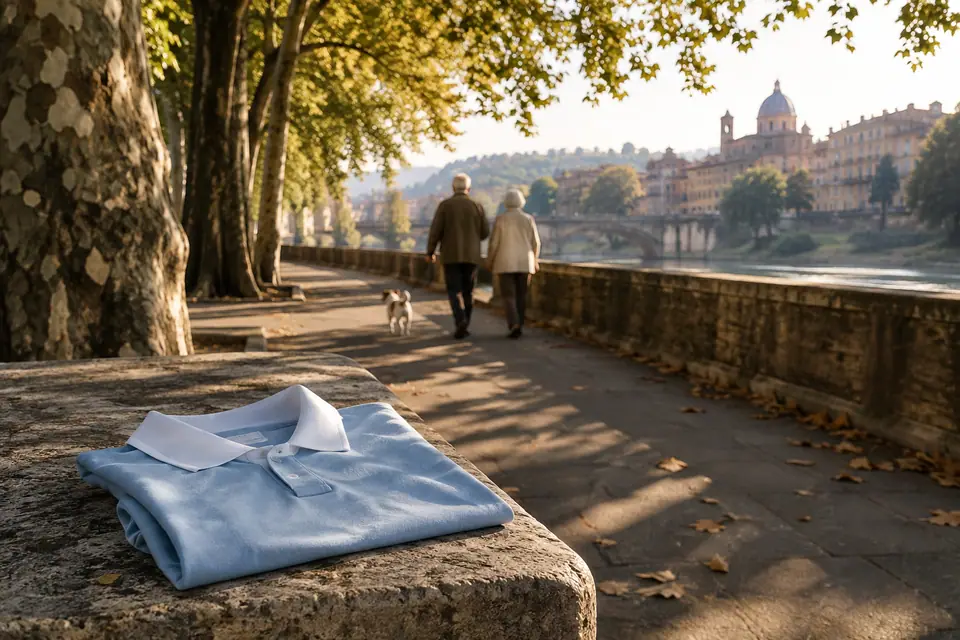Maillot de foot bleu ciel rétro plié sur un banc de pierre au bord d'un fleuve, sous les platanes