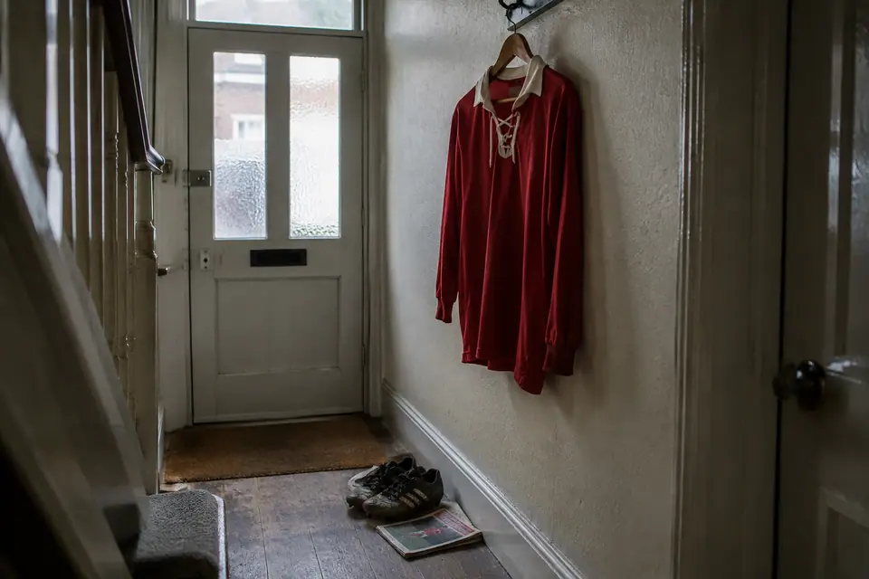 Maillot de foot rouge à col lacé suspendu dans l'entrée étroite d'une maison de brique anglaise