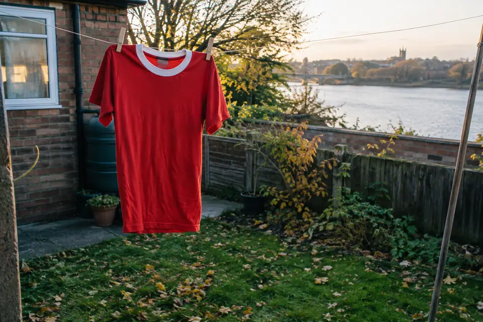 Maillot de foot rouge rétro séchant sur un fil à linge dans un petit jardin anglais en automne