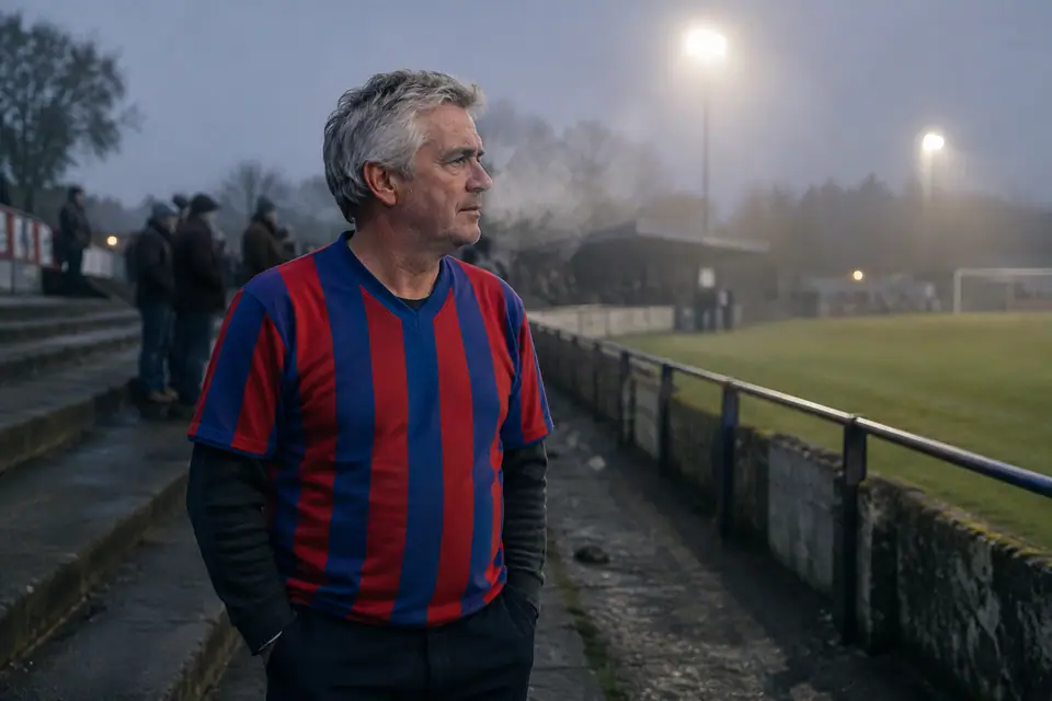 Supporter grisonnant en maillot de foot rétro rayé rouge et bleu dans une vieille tribune, un soir d'hiver