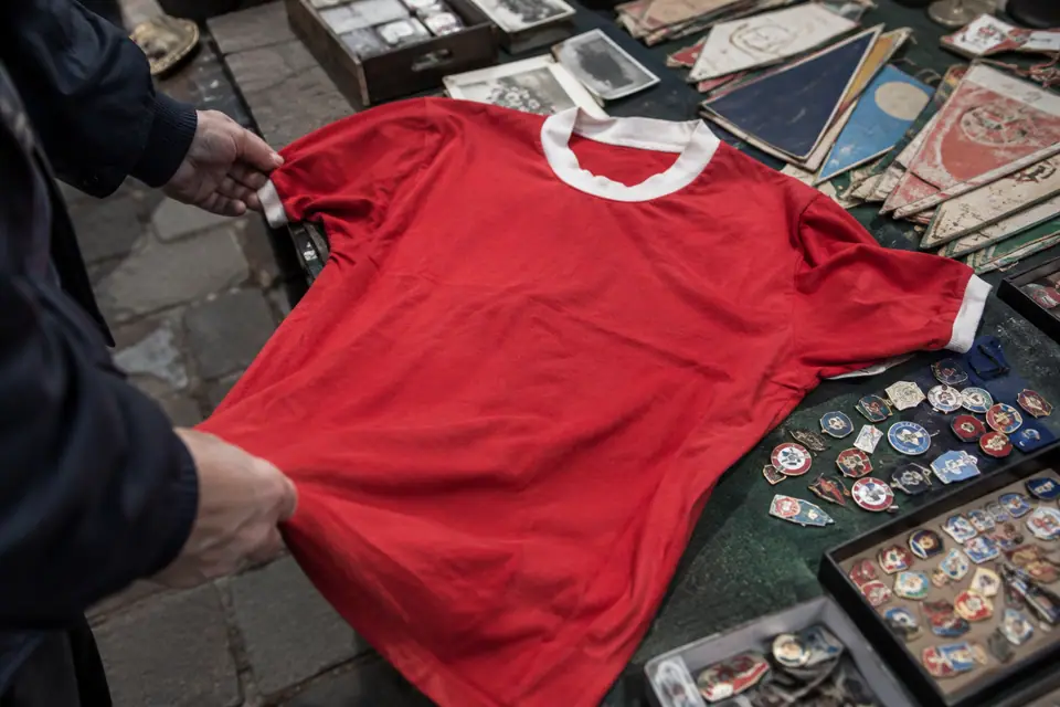 Maillot de foot rouge rétro sur une table de brocante, entre vieux insignes et fanions