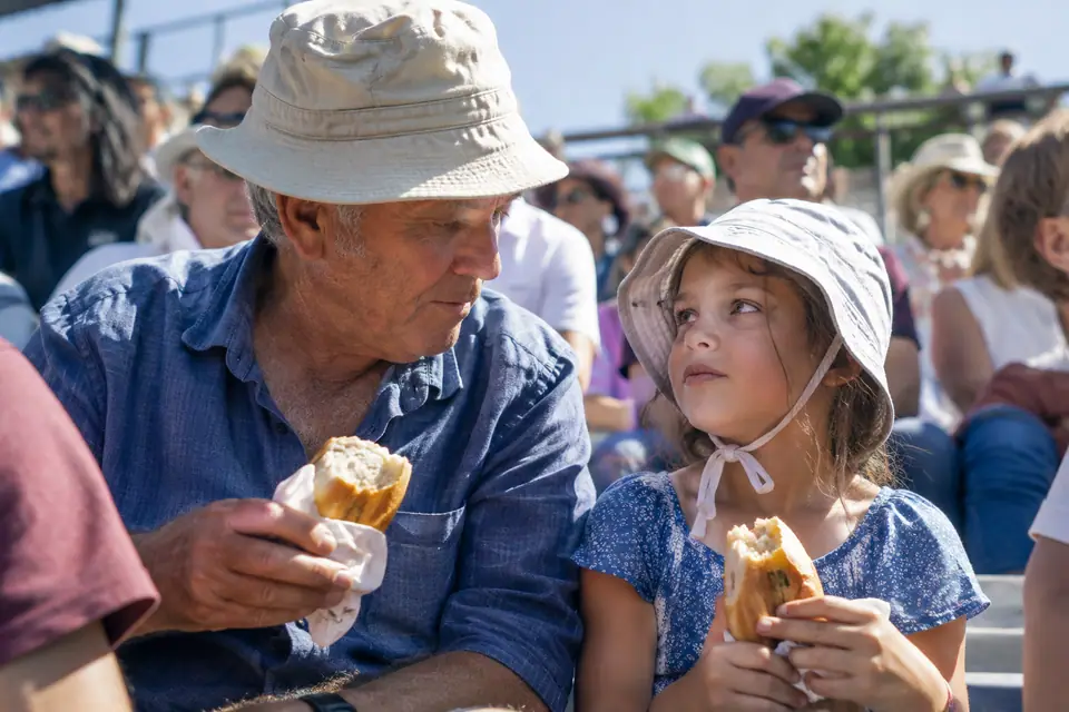 Grand-père et petite-fille coiffés de bobs en coton dans une tribune ensoleillée en plein été