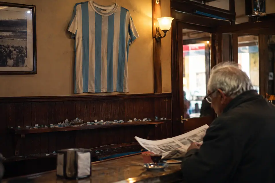 Maillot de foot à rayures bleu ciel et blanc accroché au mur d'un vieux bar de quartier