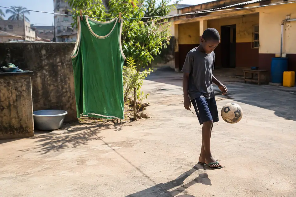 Maillot de foot vert sans manches suspendu à un fil à linge dans une cour ensoleillée