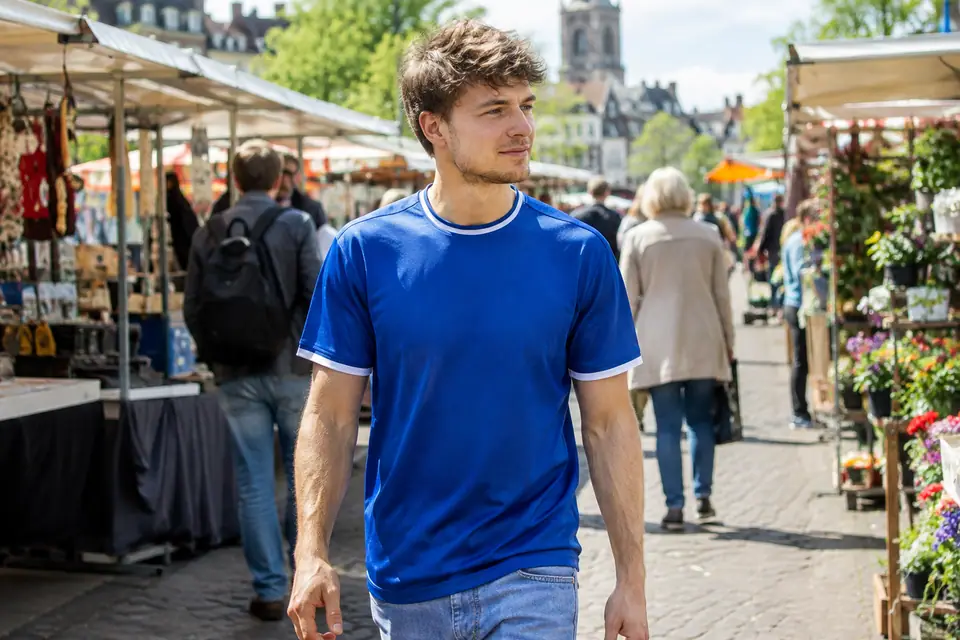 Jeune homme portant un maillot de foot bleu dans un marché en plein air